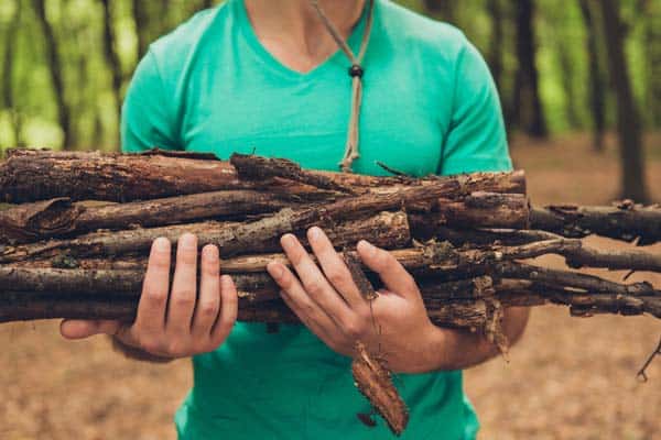 Photo of man holding a load of firewood for campfire