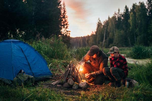 Photo of father and son building a campfire