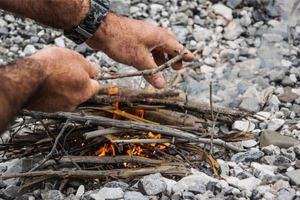 Photo of a man lighting a campfire using tinder