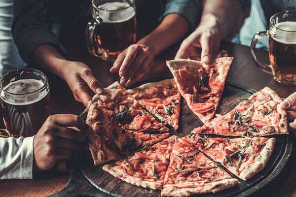 Photo of friends sharing pizza and beer