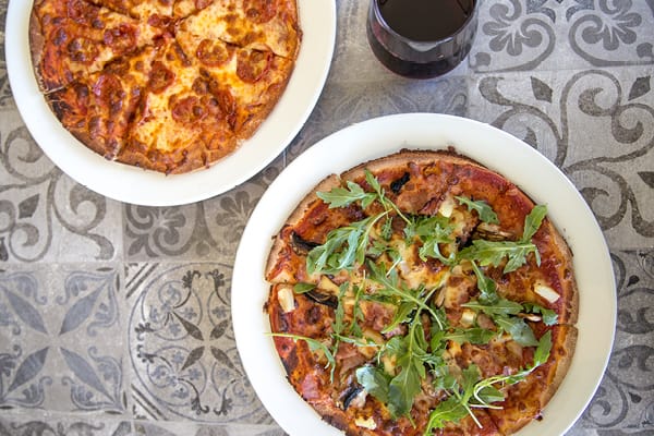 Photo of pizzas and glass of wine at Hastings Coffee Co. similar to those being served on International Pizza and Beer Day