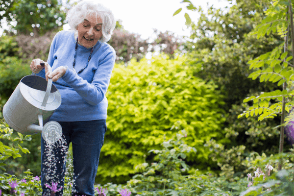 Photo of a lady watering flowers in her spring garden