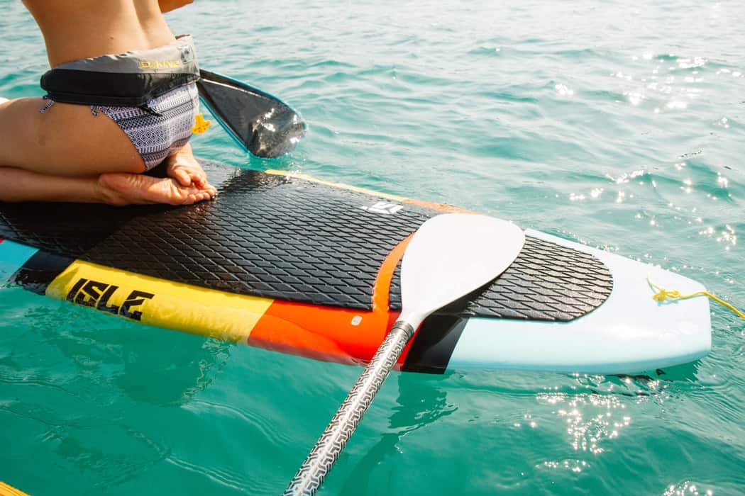 back of a girl sitting on a stand up paddle board