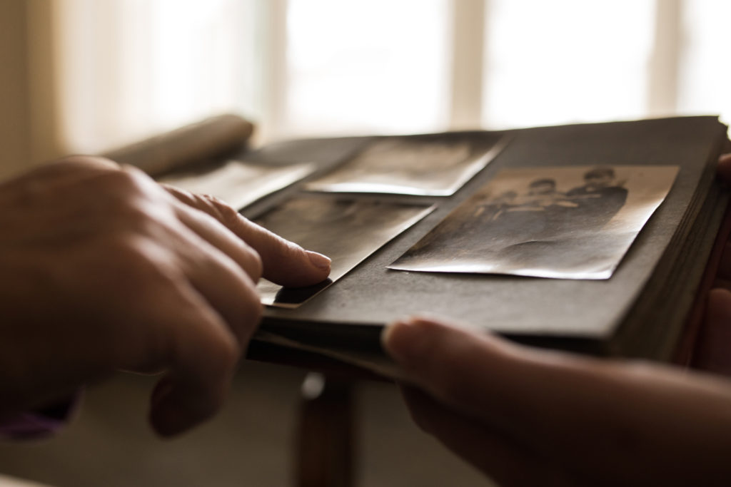 Close up unrecognizable person looking photo album pointing to one photo