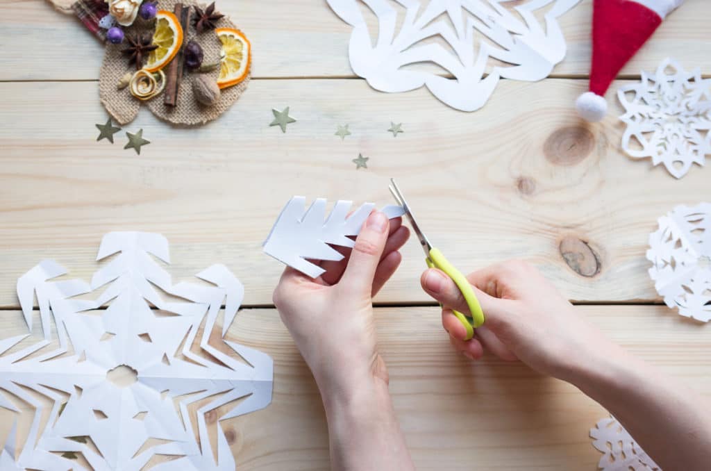 the girl makes a homemade snowflakes cut out of paper, preparation for the new year, Christmas, home decoration