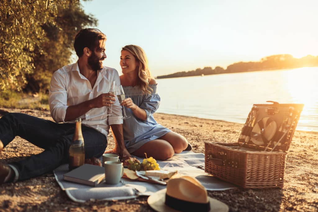 A young couple cheersing with champagne at the beach